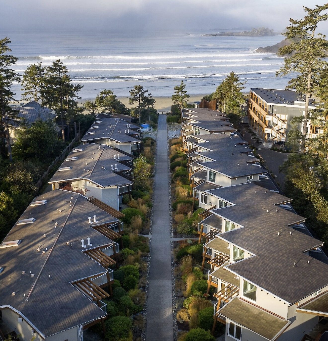 Aerial view of beachfront lodgings on a path leading to the surf at Tofino